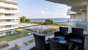 A balcony with wicker furniture overlooking a swimming pool and a view of the sea. - Apartment in Rogowo Near Beach and Lake (Trzebiatow)