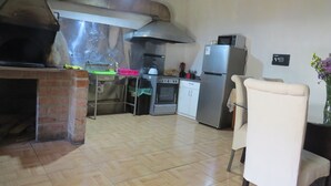 Uma cozinha com forno de tijolos, eletrodomésticos de aço inoxidável e uma área de jantar com cadeira e mesa.