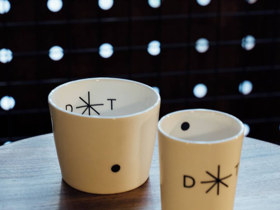 Two beige cups with symbols on a wooden table against a dark background with circular patterns.