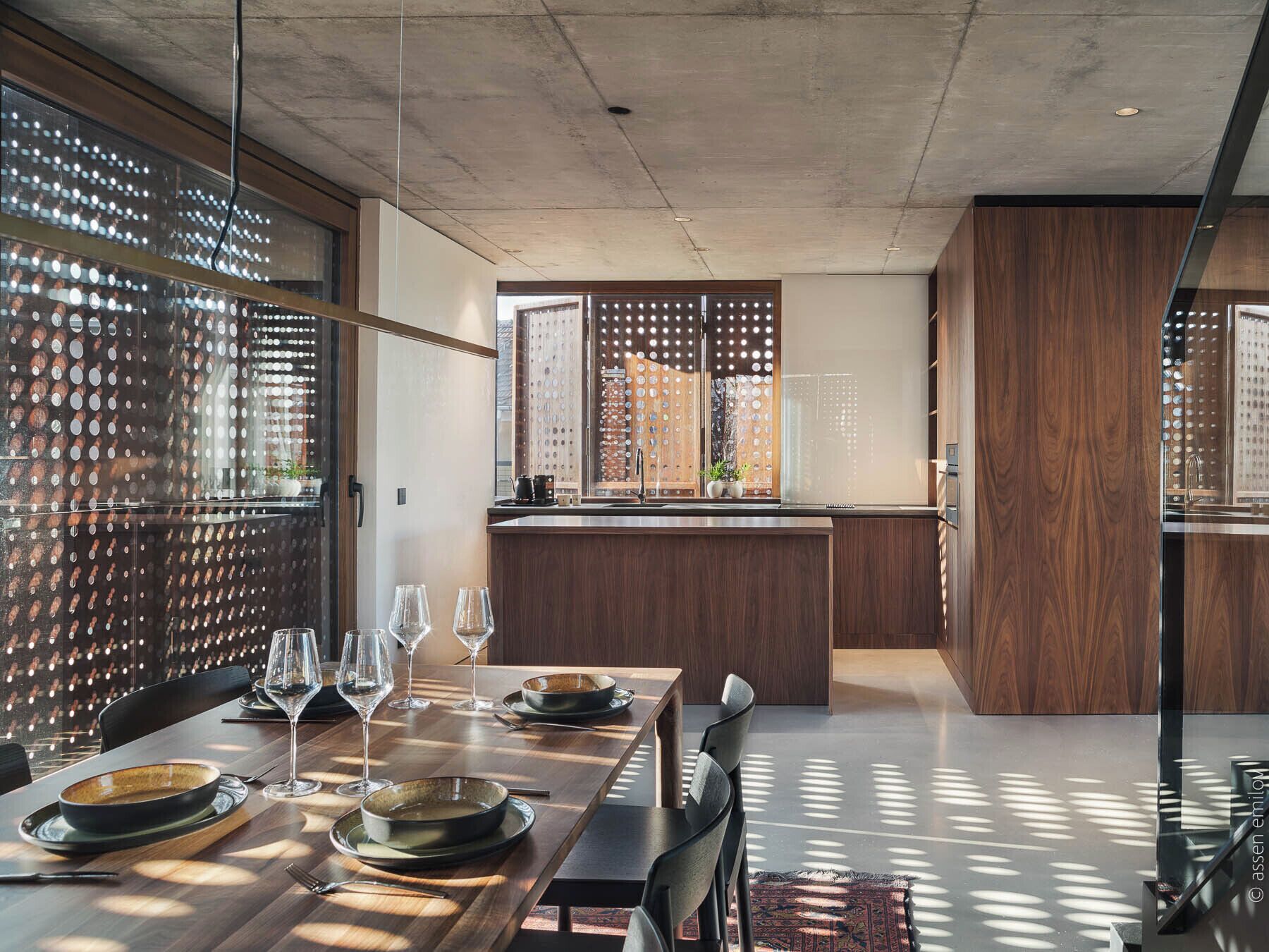 A modern kitchen with a central island, wooden cabinetry, and a dining area with a table set for four.