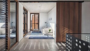 A modern interior with a concrete ceiling, a glass door leading to a balcony, a blue rug, and a white sofa. - DOT Sofia (Sofia)