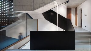 A modern staircase with a glass railing, a black platform, and a concrete ceiling. - DOT Sofia (Sofia)