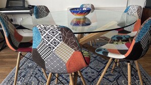A dining area with a glass-top table surrounded by chairs with patterned upholstery. - Lovely 2-bed Apartment -sleeps 5 & Parking (Dublin)