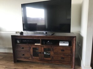 A wooden entertainment center with a flat-screen TV, a gaming console, and a laptop. - Lovely 2-bed Apartment -sleeps 5 & Parking (Dublin)