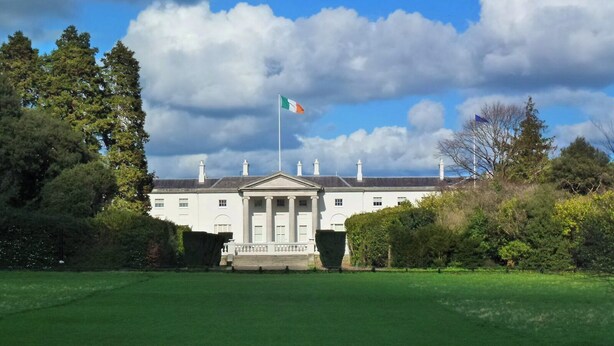A large, white building with a central entrance and columns, surrounded by lush greenery and a flag. - Lovely 2-bed Apartment -sleeps 5 & Parking (Dublin)