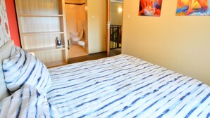 Een slaapkamer met een bed, een kledingkast en een badkamer zichtbaar door een geopende deur.