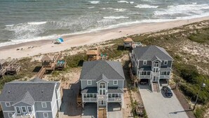 Una propiedad frente a la playa con varias casas, una playa con sombrillas y un muelle al fondo.