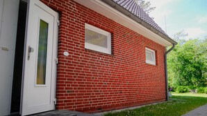 A red brick building with a white door and two small windows. - Ferienwohnung in St. Peter-ording (St. Peter-Ording)