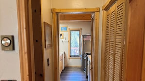 A narrow wooden hallway with a ceiling fan, a window with a view of trees, and a door with a lock. - OPEN YEAR ROUND - 3 Bedroom Lake San Cristobal Condo on the Alpine Loop (Lake City)