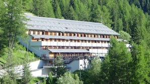 Ett hotell med flera våningar och ett platt tak, omgivet av tät skog.