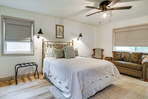 Une chambre à coucher comprenant un lit, un canapé, un ventilateur de plafond et une fenêtre avec des stores.