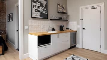 A modern kitchen with white cabinets, a wooden countertop, and a built-in dishwasher. There are two framed pictures on the wall above the counter.