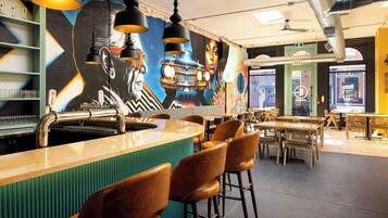 Un área de bar moderna con mostrador, taburetes y un mural en la pared.