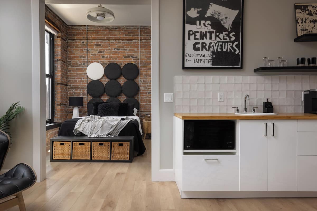 A modern kitchen with white cabinets, a wooden countertop, and a brick wall.