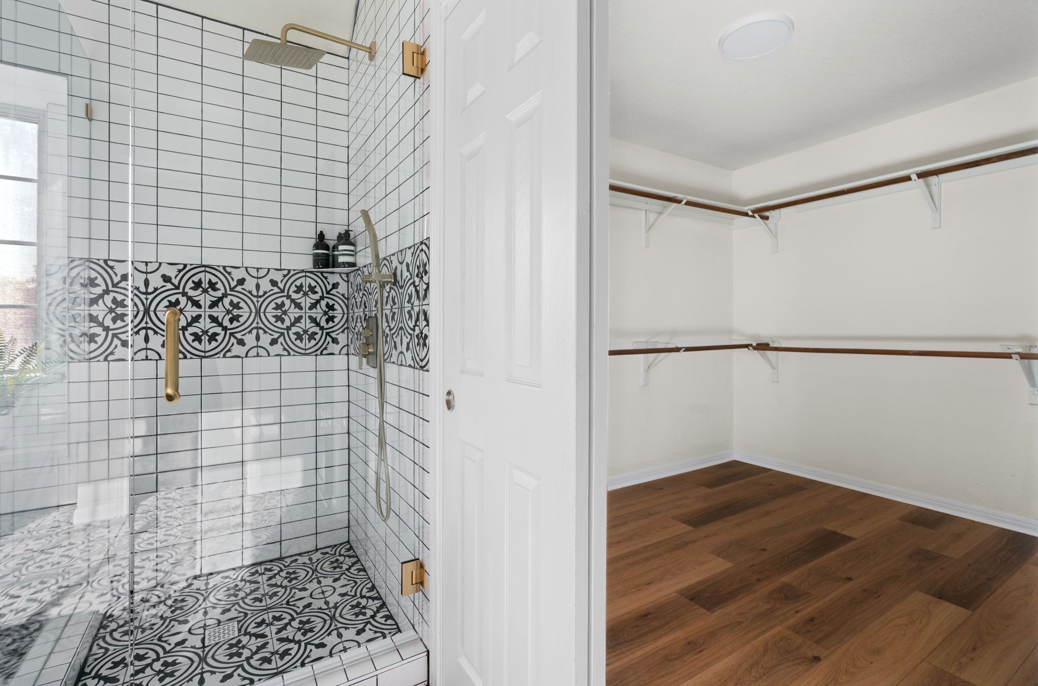 Une salle de bain avec des carreaux décorés, une douche et un plancher en bois.