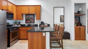 A kitchen with wooden cabinets, a black countertop, and a central island with chairs.