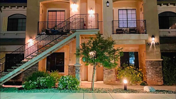 A two-story building with a balcony, a staircase, and a well-lit entrance.