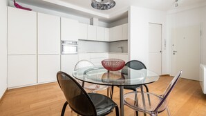A modern kitchen with white cabinetry, a glass dining table, and a unique red bowl centerpiece. - Santo Stefano Design Apartment by Wonderful Italy (Bologna)