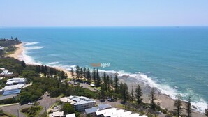 A coastal property with a beach view, a road, and a flagpole with 'localagent' text.