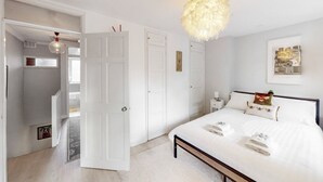 A bedroom with a bed, bedside tables, a hanging light fixture, and a door leading to a closet. - Stylish flat in West Hampstead - Pass the Keys (London)