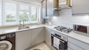 A modern kitchen with a built-in washer, a gas stove, and an oven. - Stylish flat in West Hampstead - Pass the Keys (London)