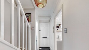 A narrow hallway with white walls, a white door at the end, and a patterned rug on the floor. - Stylish flat in West Hampstead - Pass the Keys (London)