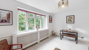 A modern living room with a large window, a radiator, a bench, and a table. - Stylish flat in West Hampstead - Pass the Keys (London)