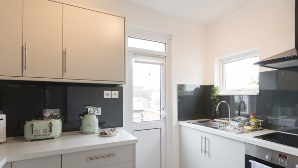 A modern kitchen with white cabinets, a built-in oven, a sink, and a toaster. - Cosy Flat in Leigh | Sea View - Pass the Keys (Southend-on-Sea)