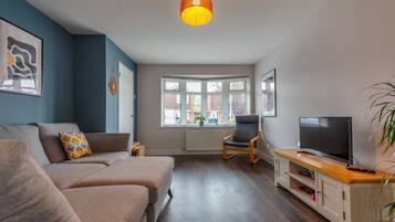 A modern living room with a sofa, TV, and a wooden cabinet.