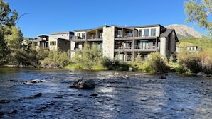 Un hôtel à plusieurs étages, doté de balcons, situé au bord d’une rivière.