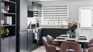 Eine moderne Küche mit schwarzen Schränken, einem eingebauten Ofen und einem Essbereich mit Tisch für vier Personen.