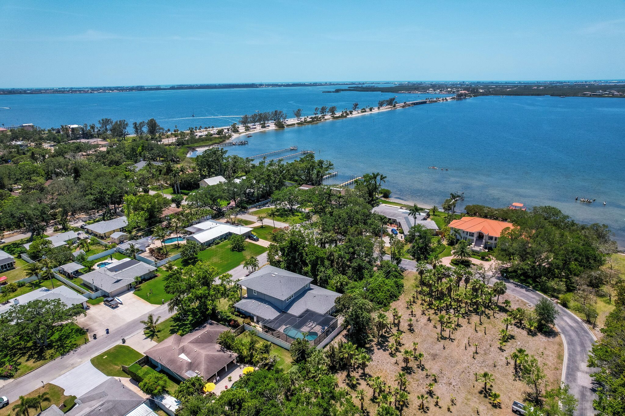 An aerial view of a coastal residential area with houses, a beach, and a pier.
