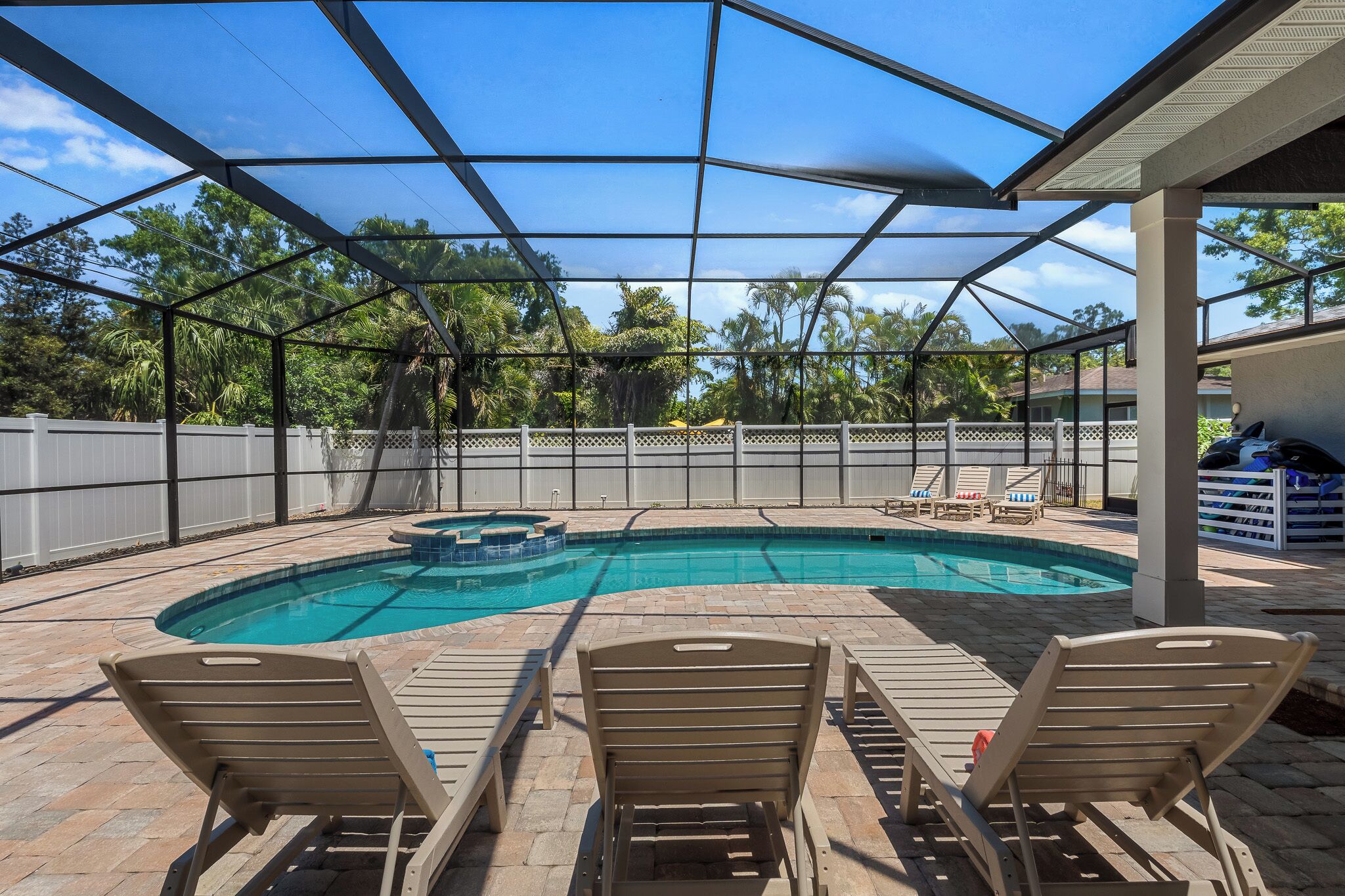 A covered swimming pool with lounge chairs and a hot tub.