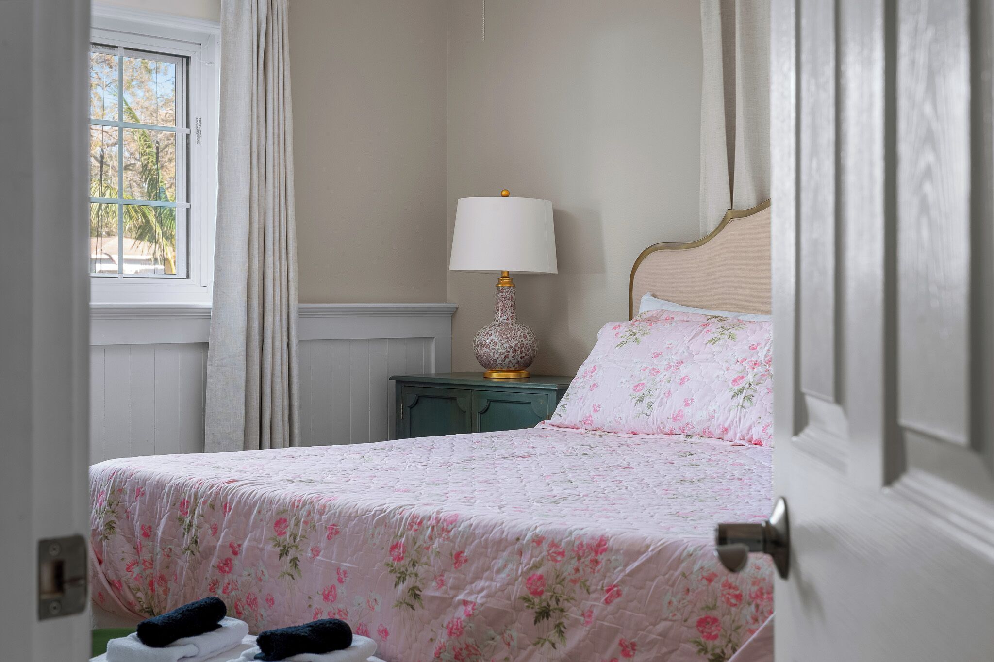 A bedroom with a bed, a nightstand, a lamp, and a window.