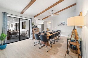 Un comedor moderno con una mesa y sillas de madera, un ventilador de techo y una estación para café.