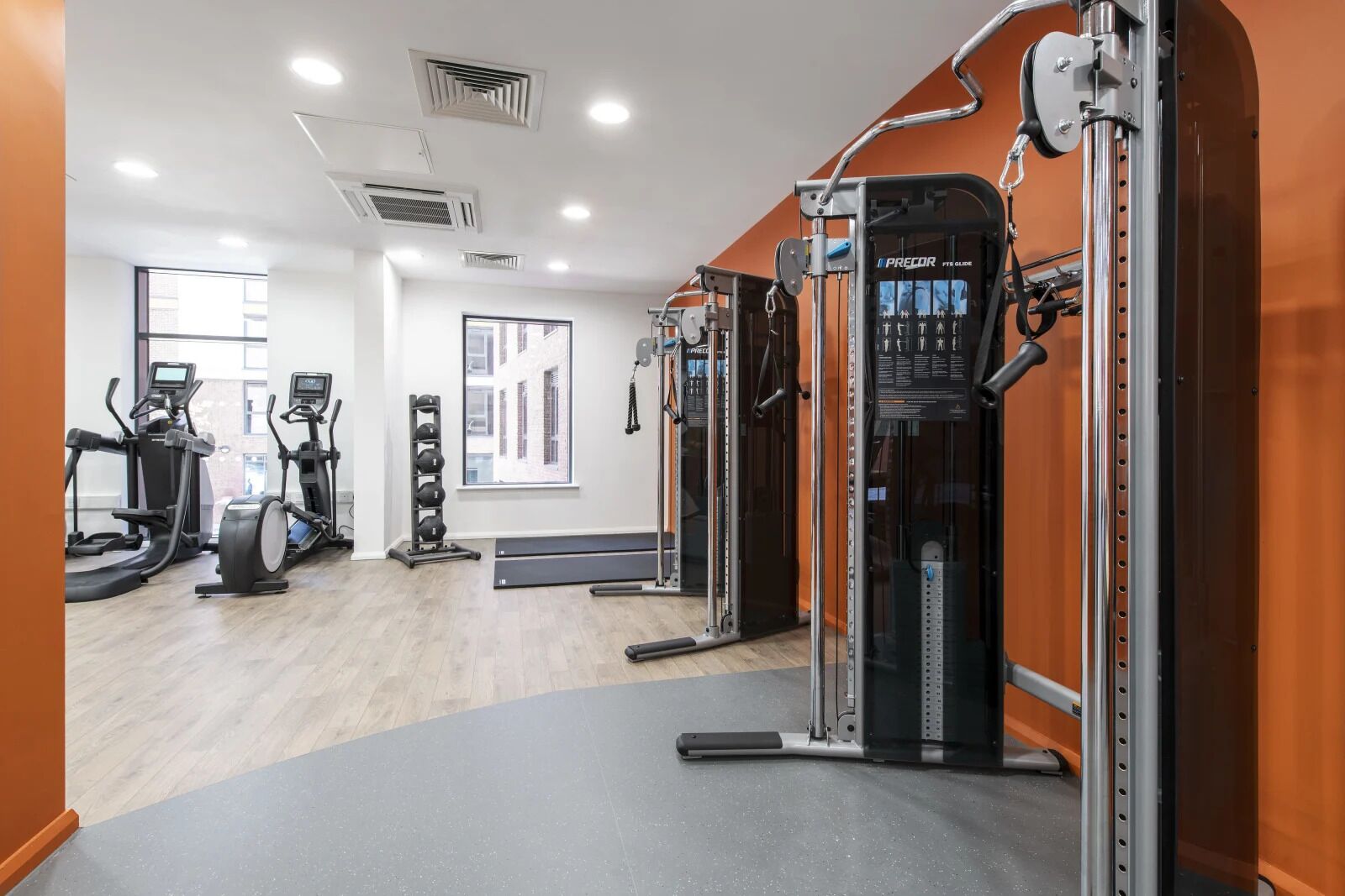 Uma academia com máquinas de cardio, equipamentos de musculação e uma grande janela.