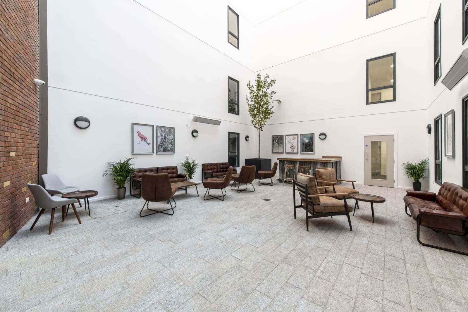 A spacious courtyard with multiple seating areas, a fireplace, and a door leading to another room.