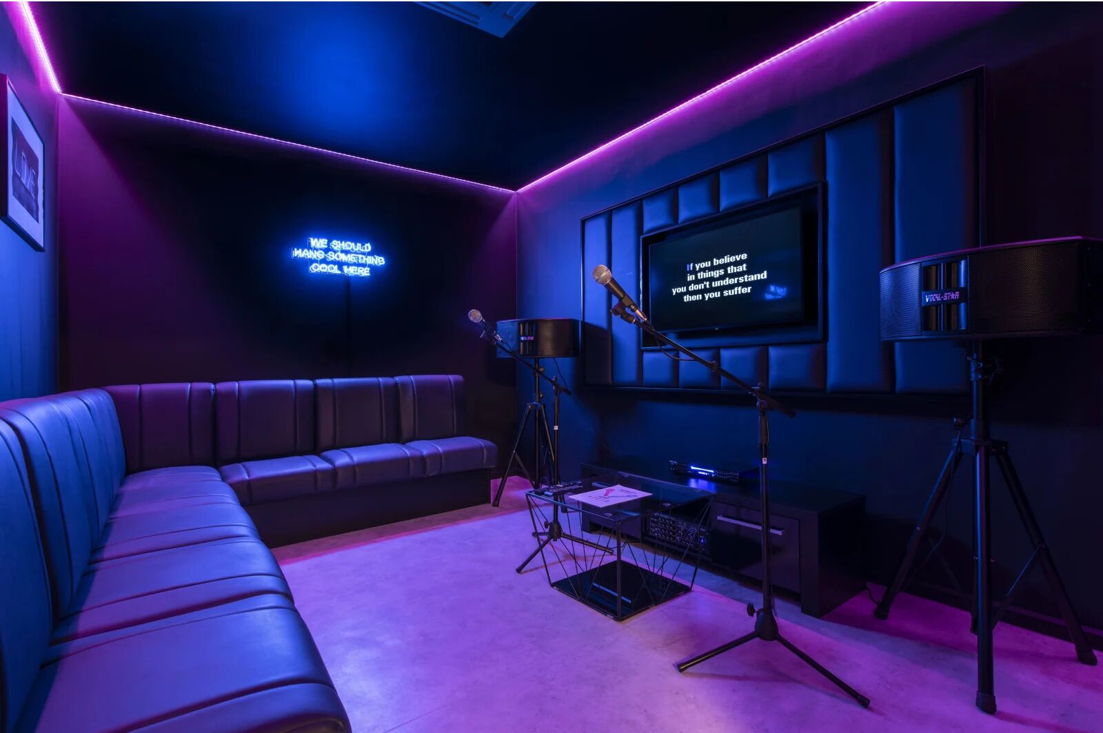 A room with a dark blue couch, a large screen displaying motivational quotes, and audio equipment.