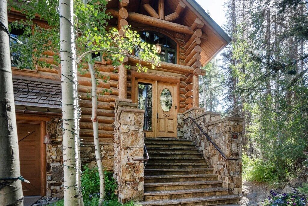 Une cabane en rondins avec un escalier en pierre menant à une porte en bois portant le numéro 225.