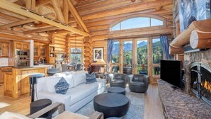 Ein rustikales Blockhaus-Interieur mit Kamin, einer Couch und einem Essbereich.