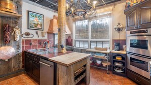 Cucina con isola in legno, elettrodomestici in acciaio inossidabile e un'ampia finestra.