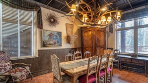 Een eethoek met een houten tafel en stoelen, een kroonluchter en een raam met uitzicht.