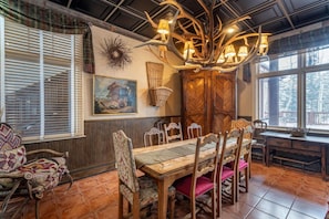 Un coin repas avec une table et des chaises en bois, un lustre et une fenêtre donnant sur un beau paysage.