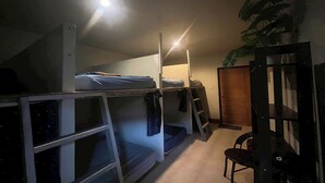 A dormitory room with bunk beds, a chair, and a potted plant. - Noah’s Ark Cannabis Bar Restaurant Hostel (Koh Samui)