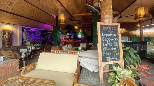 A cozy cafe with wooden furniture and a chalkboard menu listing coffee and tea options. - Noah’s Ark Cannabis Bar Restaurant Hostel (Koh Samui)