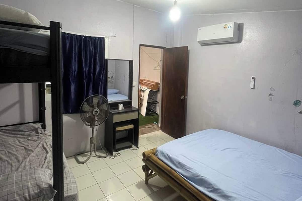 Habitación tipo dormitorio con literas, un escritorio, una silla, un ventilador y un equipo de aire acondicionado.