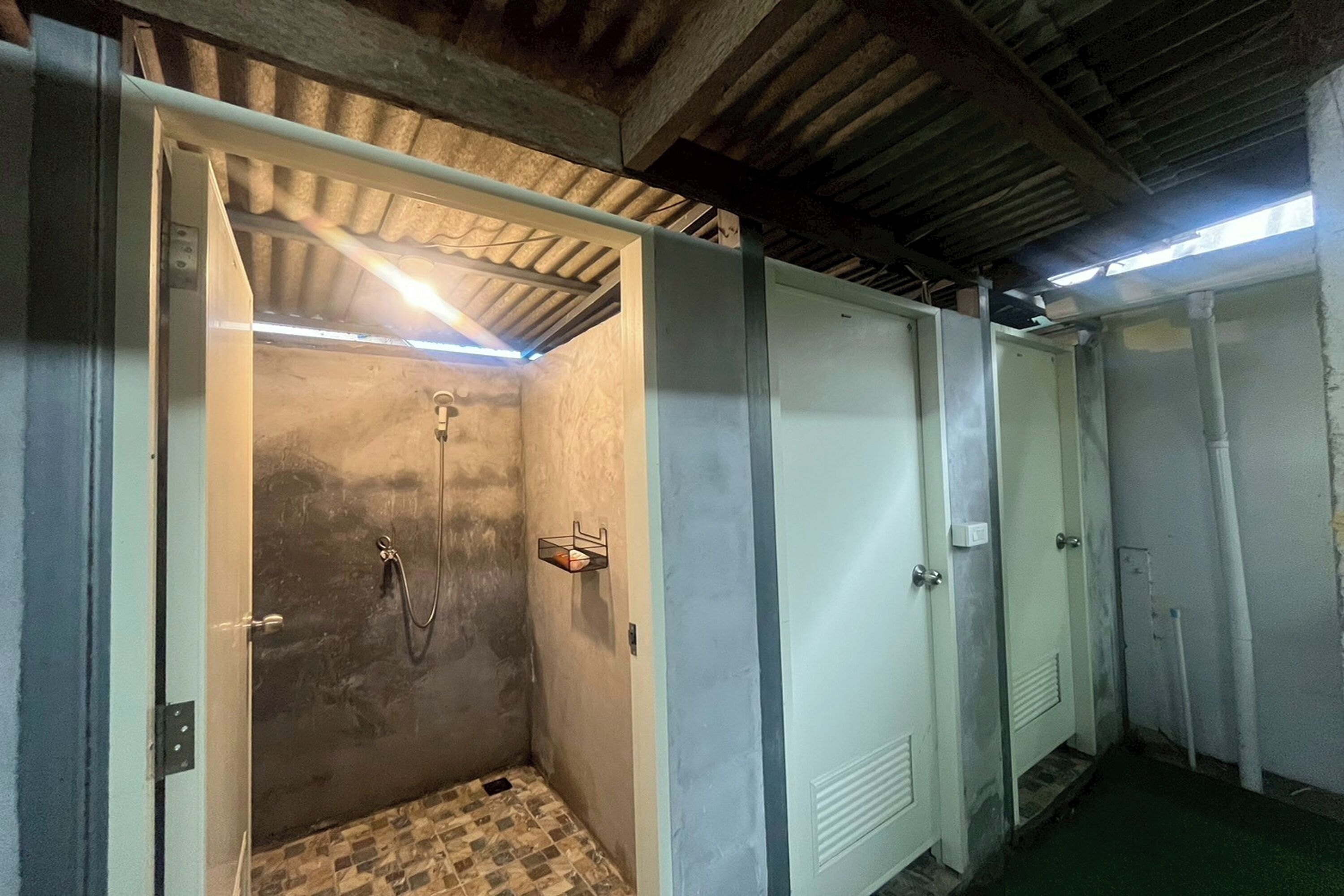 Una hilera de vestidores amplios con suelo de baldosas y techo metálico.