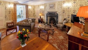 A traditional living room with a sofa, armchairs, a coffee table, and a fireplace.