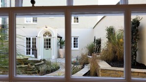 A courtyard with a central door, surrounded by plants and a brick wall.