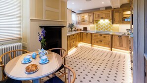 A cozy kitchen with wooden cabinets, a tiled backsplash, and a dining area with a table set for tea.